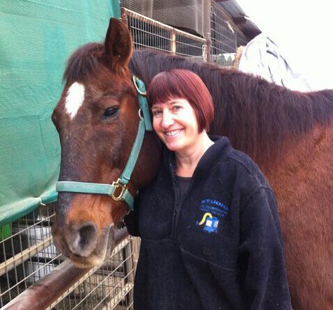 Woman smiling hugging a horse